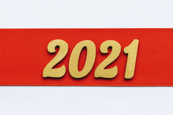 Festive background. Red ribbon with golden 2021 new year sign. Winter holiday celebration banner. Top view. Copy space. — Stock Photo, Image