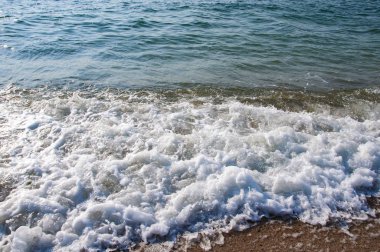 Deniz kıyısı dalgaları kum taşlar mavi gökyüzünde güzel bulutlar