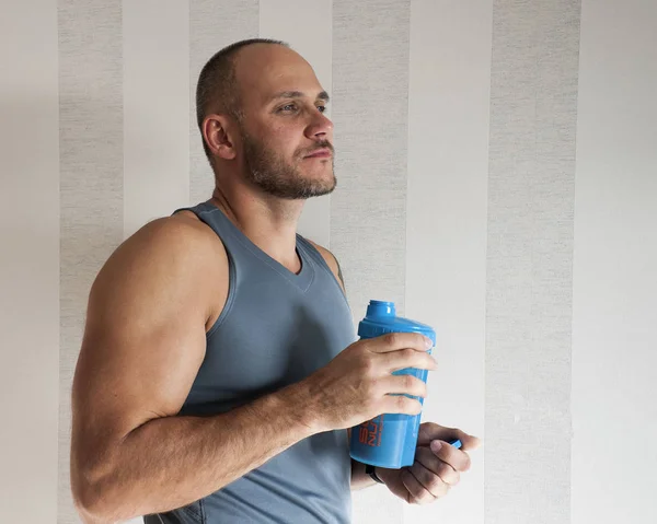 Portrait of a man with a bottle of protein shake. Athlete. Sport concept. Man in profile. Looks into the distance.