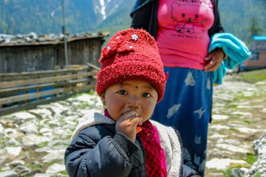 Nepal, Mayıs 2017.Sokakta kırmızı şapkalı küçük kız şeker yiyor.