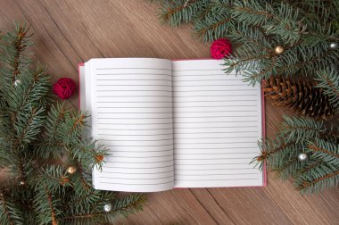 Noel ağacı dalları, koniler, kalpler, yıldızlar, ahşap bir dokuda bir defter..