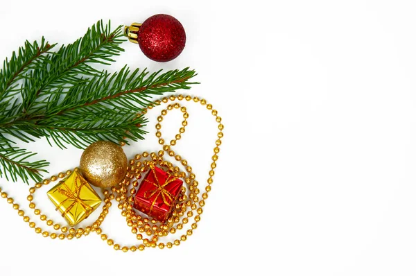 Noel ağacının dalları ve beyaz arka planda kırmızı ve sarı hediye kutuları ve toplar. Kopyalama alanı olan Noel arkaplanı