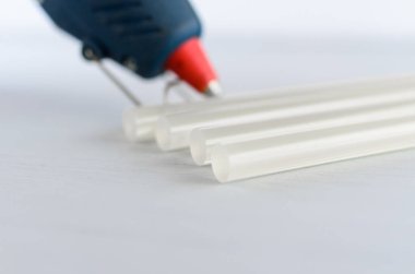 Mavi tutkal tabancası ve beyaz arka plan üzerinde sıcak eritme çubukları