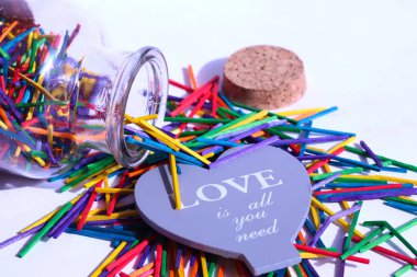 Cam birçok çok renkli ahşap çubuklar ve Aşk hakkında ifadeler ile büyük gri kalp ile şişe açıldı