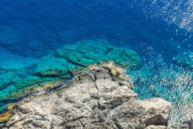 Yatay fotoğraf mavi Denizi çevresinde ile rocky resif üzerinde manzaralı. Akropolis Lindos güneşli yaz günü yakalanan Rhodos şehirdeki resif altındadır.