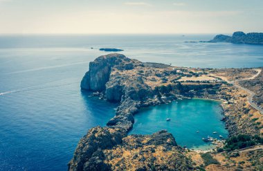 Vintage yatay fotoğraf ile Rodos Adası üzerinde güzel koy. Cove yukarıda Lindos şehrin antik Acropolis yakalanır. Birkaç şezlong kayalar tarafından gizli Cove görülebilir.