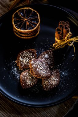 Dikey fotoğraf birkaç kahverengi tatlılar. Tatlı krema ile doldurulmuş, tarafından çikolata kaplı ve beyaz Hindistan cevizi fiş tarafından mayınları. Birkaç tarçın ve yığılmış turuncu halkalar yanındaki şeker vardır.