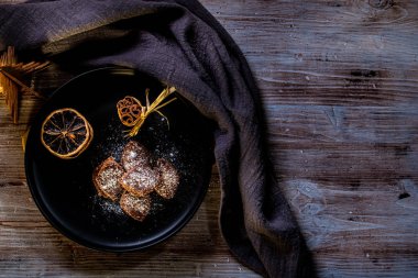 Yatay fotoğraf birkaç kahverengi tatlılar. Tatlı krema ile doldurulmuş, tarafından çikolata kaplı ve beyaz Hindistan cevizi fiş tarafından mayınları. Birkaç tarçın ve yığılmış turuncu halkalar yanındaki şeker vardır.