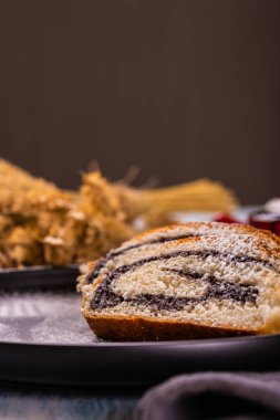 Haşhaş tohumu strudel dikey fotoğraf. Bazı bölümleri karanlık plaka üzerine yerleştirilir. toz şeker tarafından oluşturulan plaka üzerinde çatal silueti olduğunu. Gri kumaş ve Mısır kulakları ahşap tahta üzerinde çok.