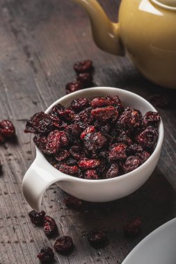 Beyaz fincan koyu ahşap tahta üzerinde yerleştirilir kurutulmuş kırmızı çilek dolu