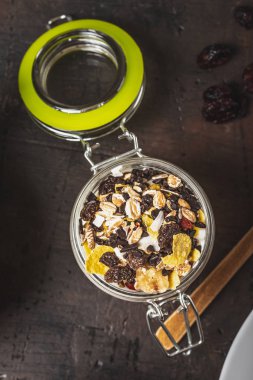 Bardağın dolu beyaz yoğurt ve koyu ahşap tahta üzerinde müsli