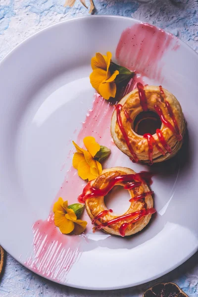 Pocas rosquillas de hojaldre con cobertura de fresa en plato blanco —  Fotos de Stock