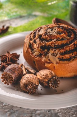 Tatlı pişmiş çörek ve baharat ile beyaz tabakta birkaç haşhaş kafaları