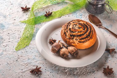 Tatlı pişmiş çörek ve baharat ile beyaz tabakta birkaç haşhaş kafaları