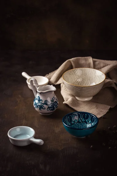 Set of ceramic bowls placed on dark wooden board with cloth — Stock Photo, Image