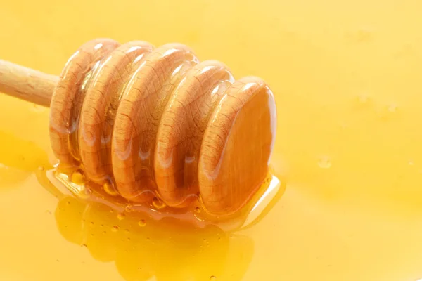 Деревянная медовая ложка или ковша закрыта на желтый жидкий мед — стоковое фото
