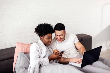 Çok ırklı bir çift sabahın erken saatlerinde dizüstü bilgisayar kullanıyor.
