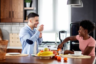 Mutfaktaki çift gülümseyip meyve suyu yapıyor.