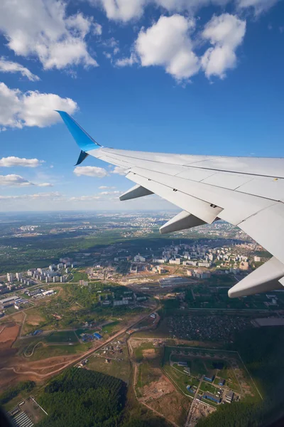 View from the elluminator of the aircraft on a sunny day on the city from above, blue sky with clouds.