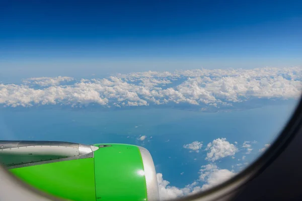 View from the elluminator of the aircraft on a sunny day on the city from above, blue sky with clouds.