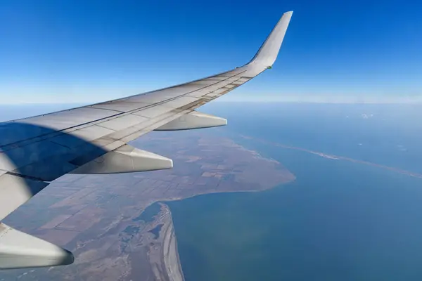 View from the elluminator of the aircraft on a sunny day on the city from above, blue sky with clouds.