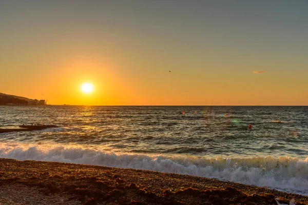 Dawn on the pebble beach of Yalta, against the background of the blue sea and flying birds in the sky.