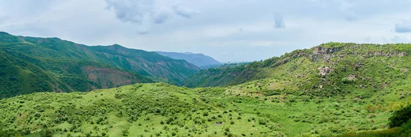 View of a green valley in the mountains on a sunny day with clou