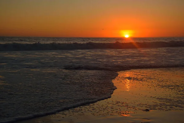 Puesta de sol naranja sobre las olas en la playa de Santa Mónica, California, EE.UU. — Foto de Stock