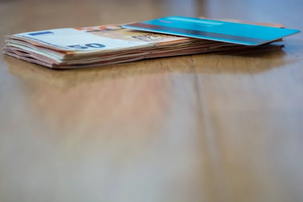 Un fajo de billetes de 50 euros en comparación con una tarjeta de crédito azul. Concepto de comparación de pago — Foto de Stock