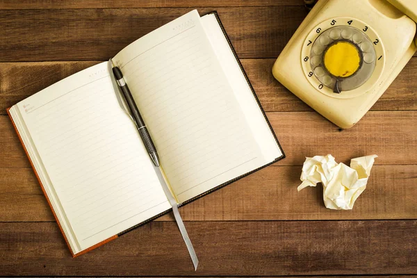 Bovenaanzicht van notebook op de houten tafel, typemachine, oude telefo — Stockfoto