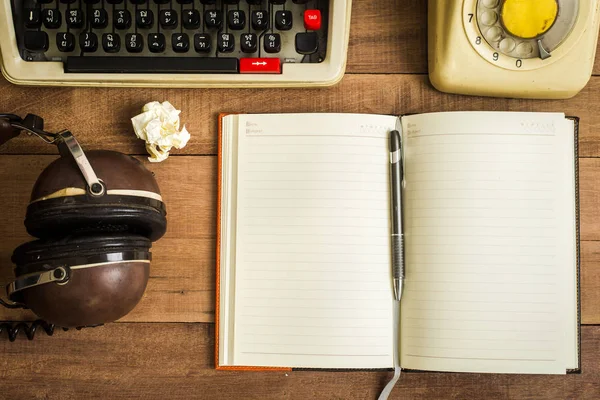 Bovenaanzicht van notebook op de houten tafel, typemachine, oude telefo — Stockfoto