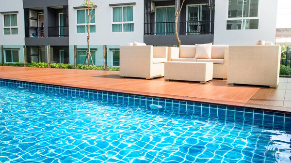 Relaxing rattan chairs with pillows beside swimming pool