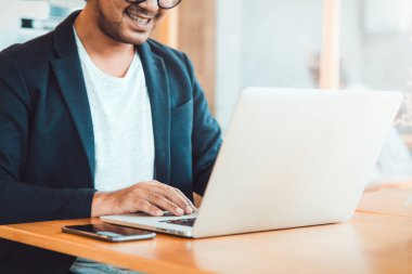 genç adam, gözlük takan ve gülümseyen, onun lapto üzerinde çalışırken