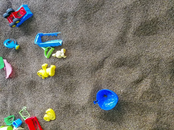 Több színű műanyag játékok a homokban. Gyermekeknek szóló játékok a homokban és a strandon. Vödör, ásó és gereblye — Stock Fotó