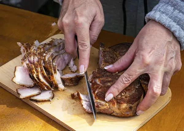 Девушка режет ветчину на пикнике. Нарезанное мясо свинины. Нарезать и перекусить на природе . — стоковое фото