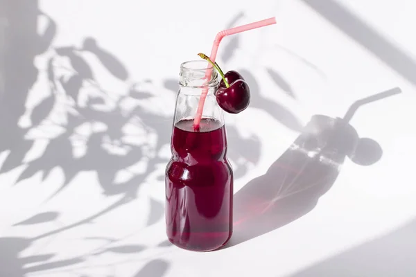 樱桃汁放在蓝色底色的瓶子里 一种新鲜的甜浆果饮料 成熟的红樱桃 — 图库照片