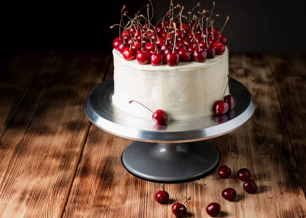 Kuchen "roter Samt", sehr schön, mit einer Süßkirsche, auf dunklem Hintergrund und einem hellen Holztisch — Stockfoto