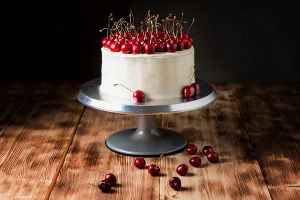 Торт "Красный бархат", очень красивый, со сладкой вишней, на темном фоне и светлом деревянном столе — стоковое фото