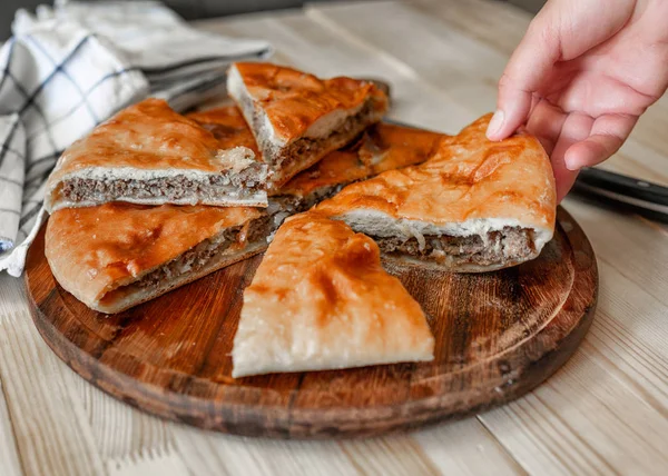 Pasteles tradicionales de carne de Osetia con carne de res con una mano femenina — Foto de Stock