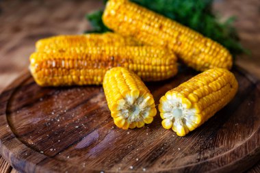 Izgara sıcak Mısır koçan yuvarlak kesme tahtası plaka ahşap masa arka plan yatıyor