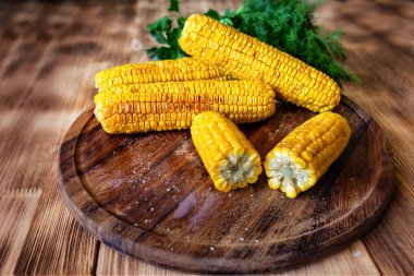 Izgara sıcak Mısır koçan yuvarlak kesme tahtası üzerinde yatıyor 