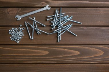 Çelik anahtar aracının yanında ahşap plakalar üzerinde yatan uzun krom cıvatalar ve somunlar