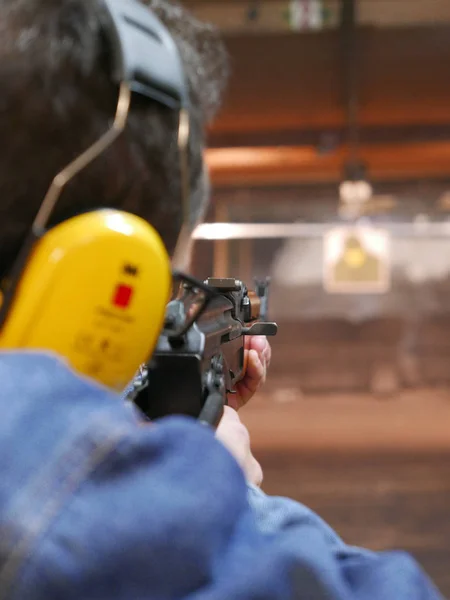 Man shooting a kalashnikov rifle in shooting range. The man is pointing at distant target.