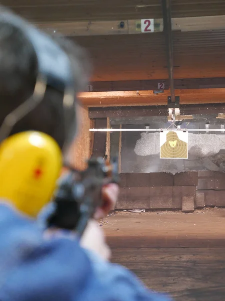 Man shooting a kalashnikov rifle in shooting range. The man is pointing at distant target.