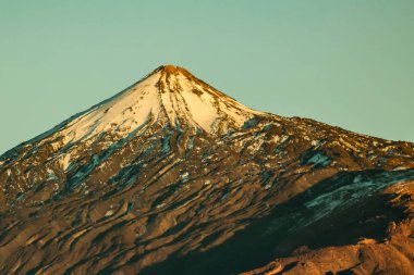 Beyaz kar lekeleri ile dağ Teide, kısmen bulutlar kaplı. Parlak mavi gökyüzü. Teide National Park, Tenerife, Kanarya Adaları, Ispanya.