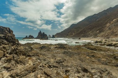 Dik yüksek lav kaya kayalıkları. Mavi deniz ufukta, doğal gökyüzü arka plan.