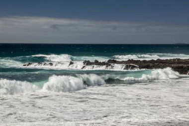 Dik yüksek lav kaya kayalıkları. Mavi deniz ufukta, doğal gökyüzü arka plan.