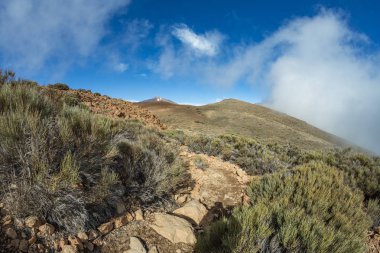 Beyaz kar lekeleri ile dağ Teide, kısmen bulutlar kaplı. Parlak mavi gökyüzü. Teide National Park, Tenerife, Kanarya Adaları, Ispanya.