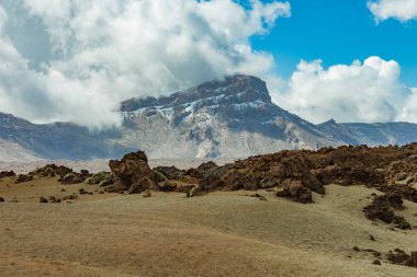 Beyaz kar lekeleri ile dağ Teide, kısmen bulutlar kaplı. Parlak mavi gökyüzü. Teide National Park, Tenerife, Kanarya Adaları, Ispanya.