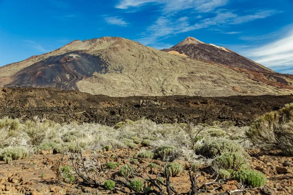 Berg Teide met witte sneeuw vlekken, deels bedekt door de wolken. Heldere blauwe hemel. Nationaal Park Teide, Tenerife, Canarische eilanden, Spanje. — Stockfoto